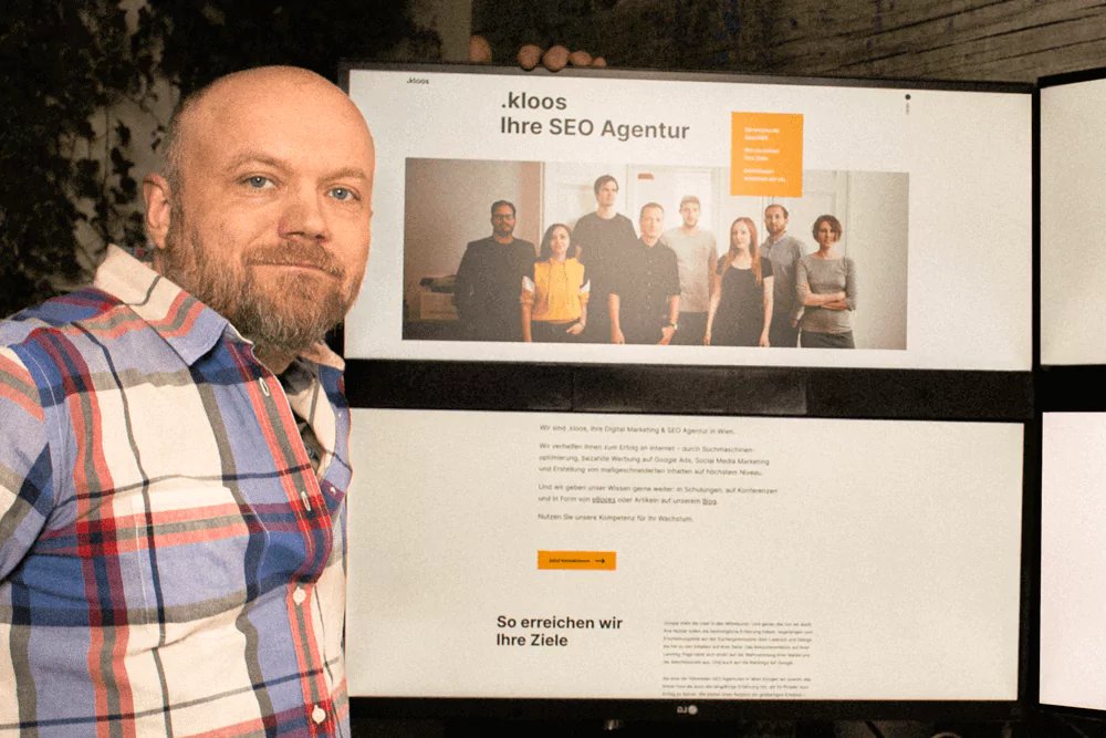 Man sitting in front of a PC that shows the kloos website